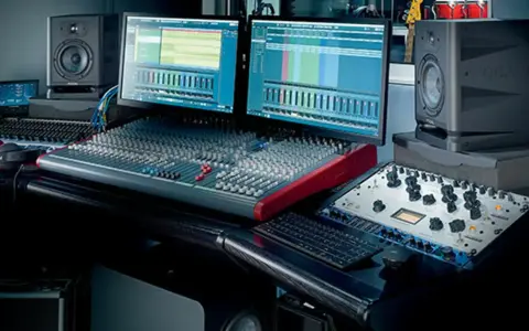 Studio d'enregistrement avec deux écrans affichant des pistes audio, une console de mixage, des enceintes Focal et du matériel pour cree une prod.