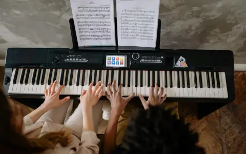 Deux mains jouent un accord c/b piano, des partitions sur le pupitre.