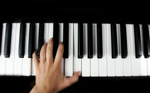 Main gauche jouant le sol 7 piano, doigts effleurant les touches noires et blanches.