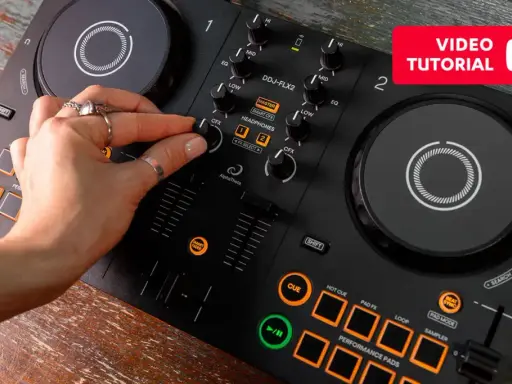 Main d'une personne manipulant une table de mixage pour créer sa propre musique électro. Tutoriel vidéo disponible.