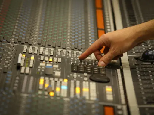 Main d'un ingénieur du son ajustant les faders d'une console de mixage, créant un son audio mono parfait.