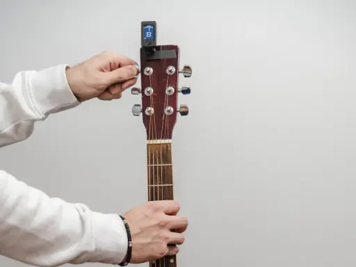 Main tenant de la guitare, il utilise un accordeur pour accorder l'instrument.