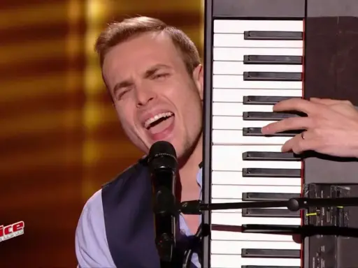 Un chanteur interprète une musique à faire au piano, sa voix résonne dans la salle.