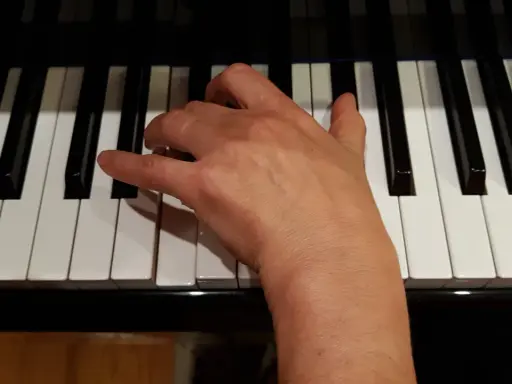 Main droite jouant un accord de ré mineur sur un piano.