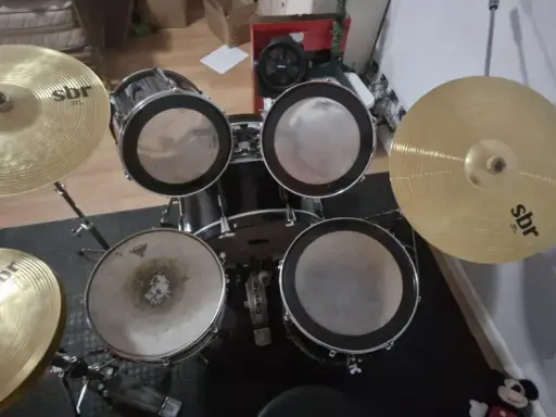 Un kit de batterie SBR avec cymbales brillantes, prêt pour que Tom aiguille les rythmes.