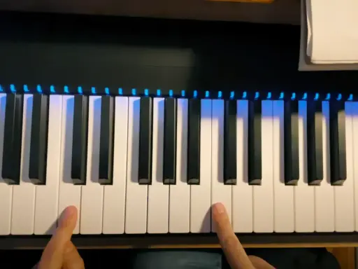 Les doigts prêts à jouer des notes sur un clavier de piano illuminé.
