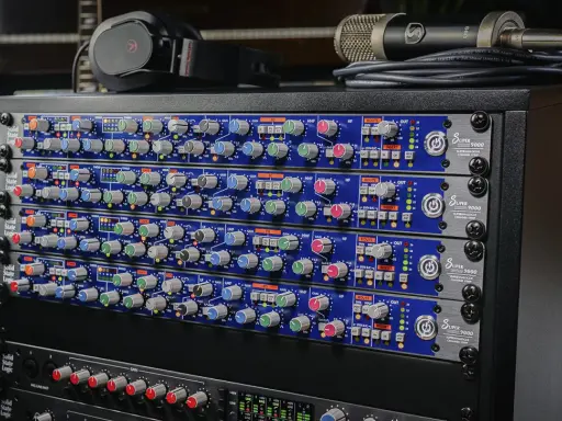 Rack de matériel audio avec plusieurs modules SSL Super 9000, un microphone et un casque.