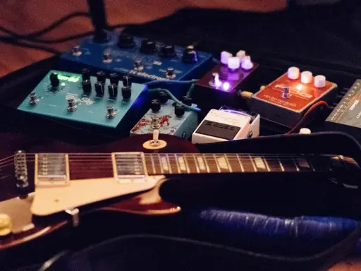Guitare électrique et pédales d'effets, dont un sustainer guitare, prêtes pour la scène.