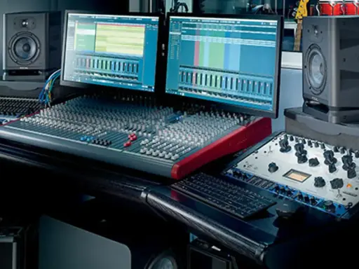 Studio d'enregistrement avec deux écrans affichant des pistes audio, une console de mixage, des enceintes Focal et du matériel pour cree une prod.
