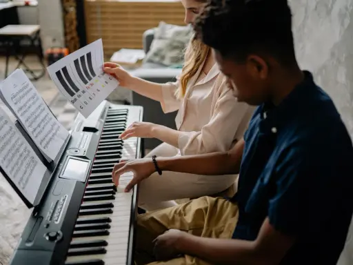 Deux jeunes jouent du piano, l'un tenant une partition montrant l'accord D7.