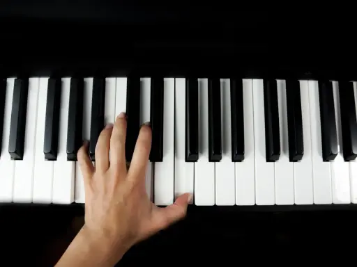 Main gauche jouant le sol 7 piano, doigts effleurant les touches noires et blanches.