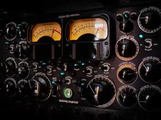 Panneau de compresseur mastering avec deux VU-mètres lumineux. Apprenez comment utiliser un compresseur en ajustant les nombreux boutons et sélecteurs.
