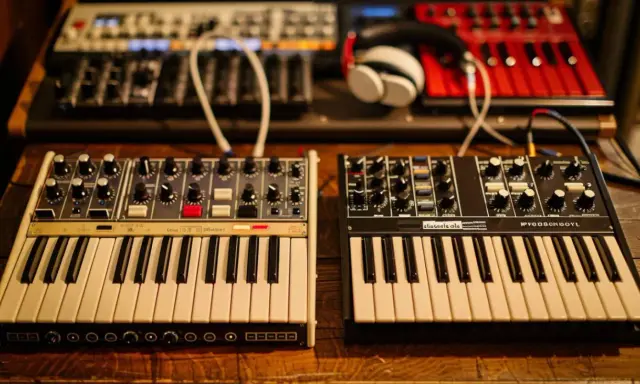 Deux synthétiseurs, l'un blanc et l'autre noir, sont alignés. Leurs claviers et boutons invitent à explorer les mondes analogique et numérique de la musique.