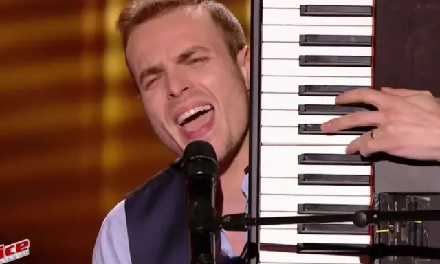 Un chanteur interprète une musique à faire au piano, sa voix résonne dans la salle.