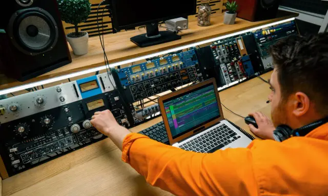 Un ingénieur du son ajuste les réglages sur une console audio, maîtrisant son studio pour un mixage parfait.