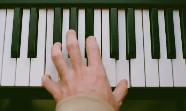 Main d'un pianiste sur des touches noires et blanches, symbolisant le passage de l'analogique au numérique.
