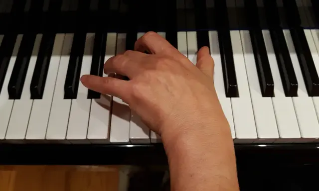 Main droite jouant un accord de ré mineur sur un piano.