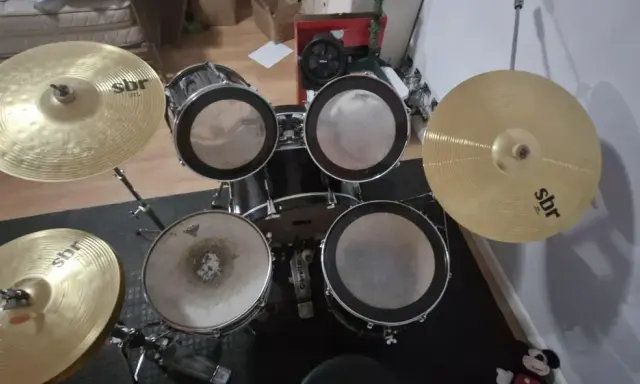 Un kit de batterie SBR avec cymbales brillantes, prêt pour que Tom aiguille les rythmes.