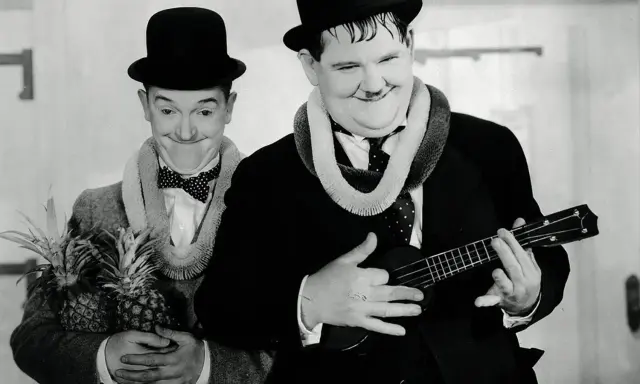 Laurel et Hardy, l'un tenant des ananas, l'autre jouant d'un ukulélé, évoquent l'origine hawaïenne de cet instrument.