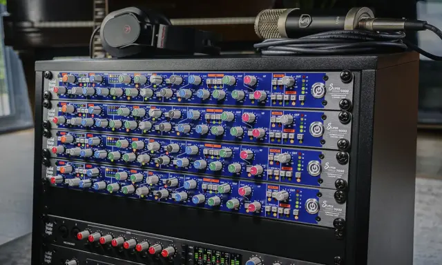 Rack de matériel audio avec plusieurs modules SSL Super 9000, un microphone et un casque.