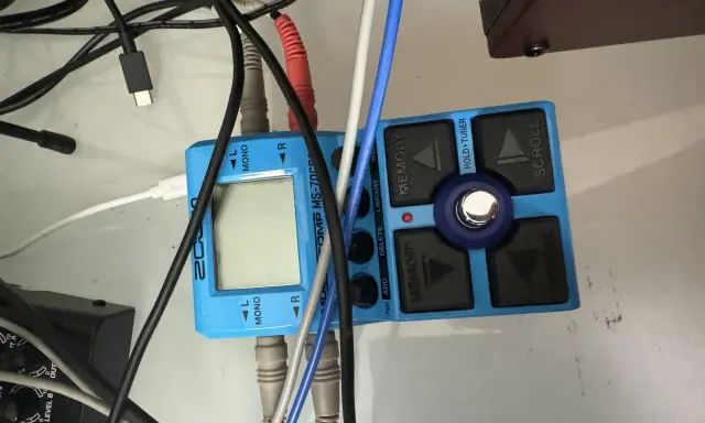 Pédalier Zoom MS-70CDR bleu avec câbles. Les entrées sont marquées L MONO et R, suggérant des options mono et stéréo pour le traitement du son.