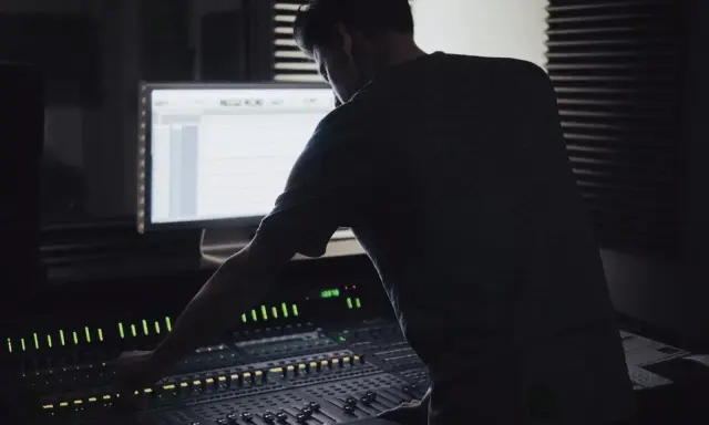 Un ingénieur du son ajuste la console, créant un mixage audio de qualité mp3 320 kbps.