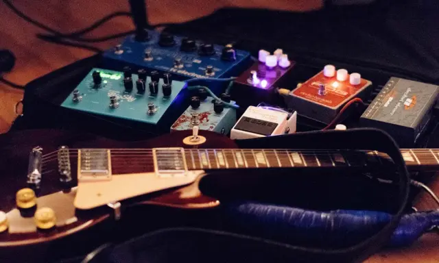 Guitare électrique et pédales d'effets, dont un sustainer guitare, prêtes pour la scène.