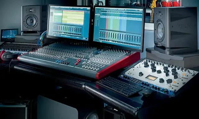 Studio d'enregistrement avec deux écrans affichant des pistes audio, une console de mixage, des enceintes Focal et du matériel pour cree une prod.