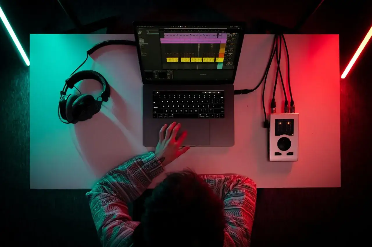 Un producteur de musique crée des sons sur son ordinateur, avec des écouteurs et une interface audio.