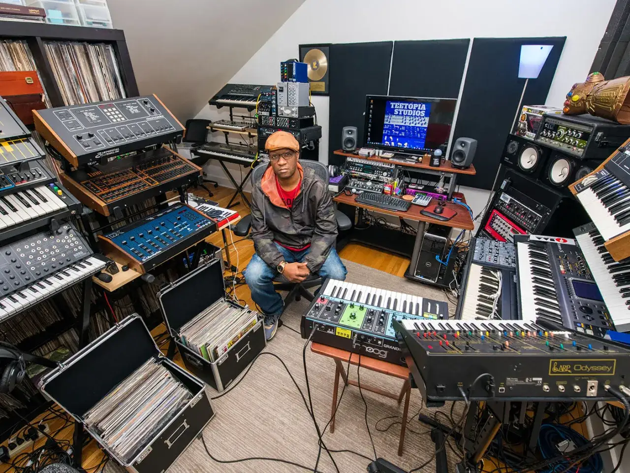 Un homme est assis dans un studio rempli de synthétiseurs techno, prêt à créer des sons.