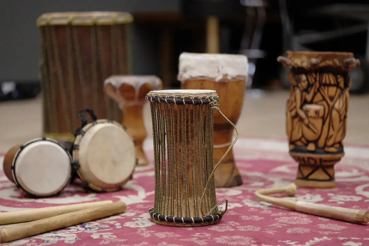 Ensemble de percussions africaines, incluant des djembés et un tambour sculpté, prêts pour une session musicale.