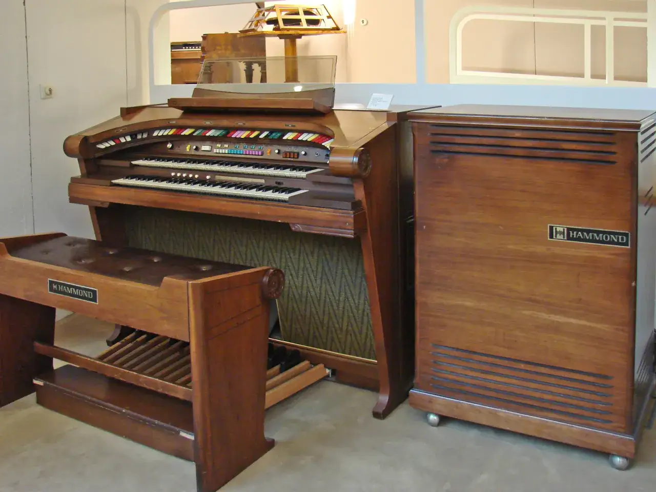 Un orgue Hammond en bois, avec ses deux claviers, son siège et son haut-parleur, prêt à faire vibrer la pièce.