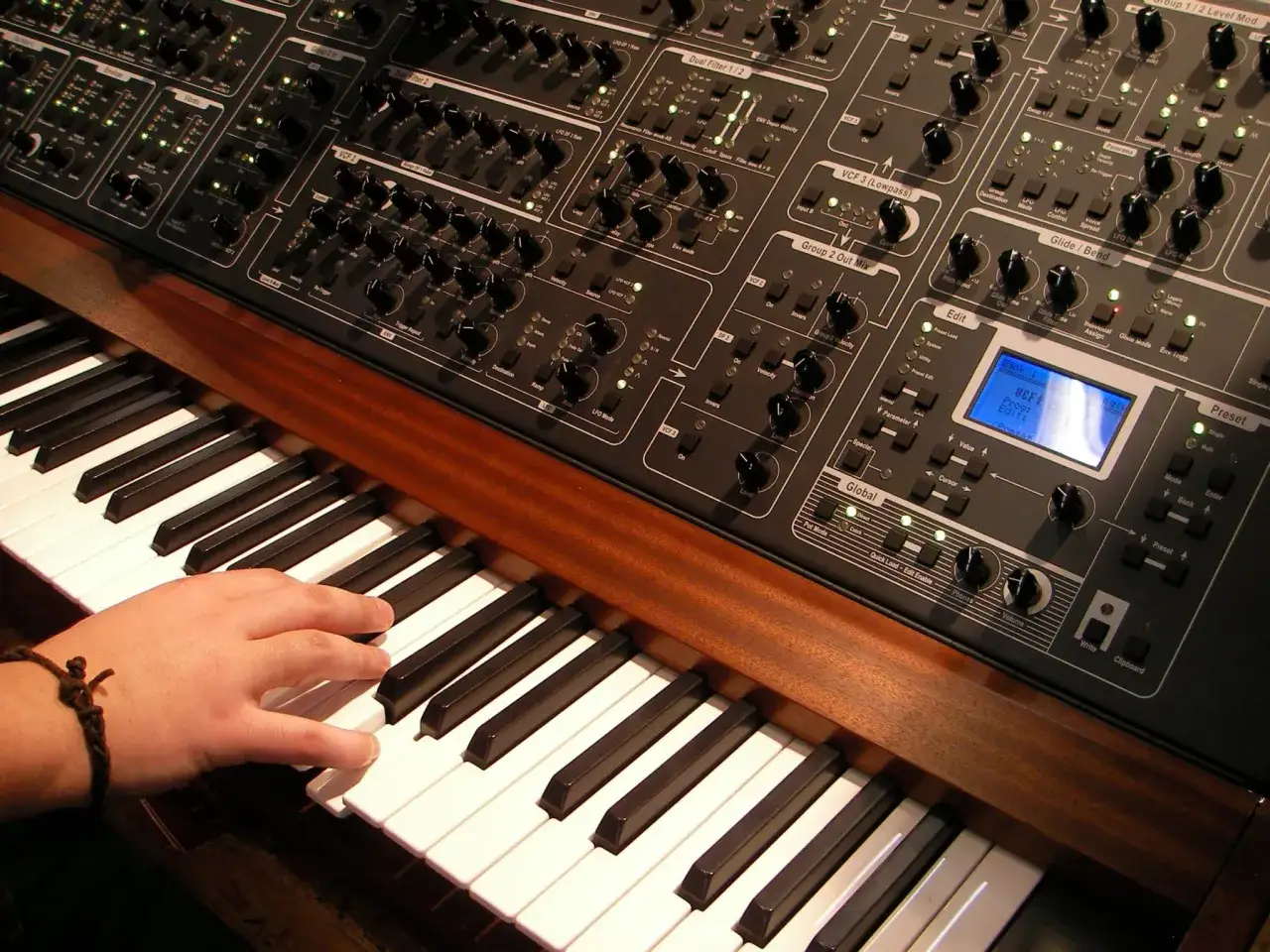 Main d'une personne jouant sur un synthétiseur analogique, explorant les possibilités sonores de son clavier.